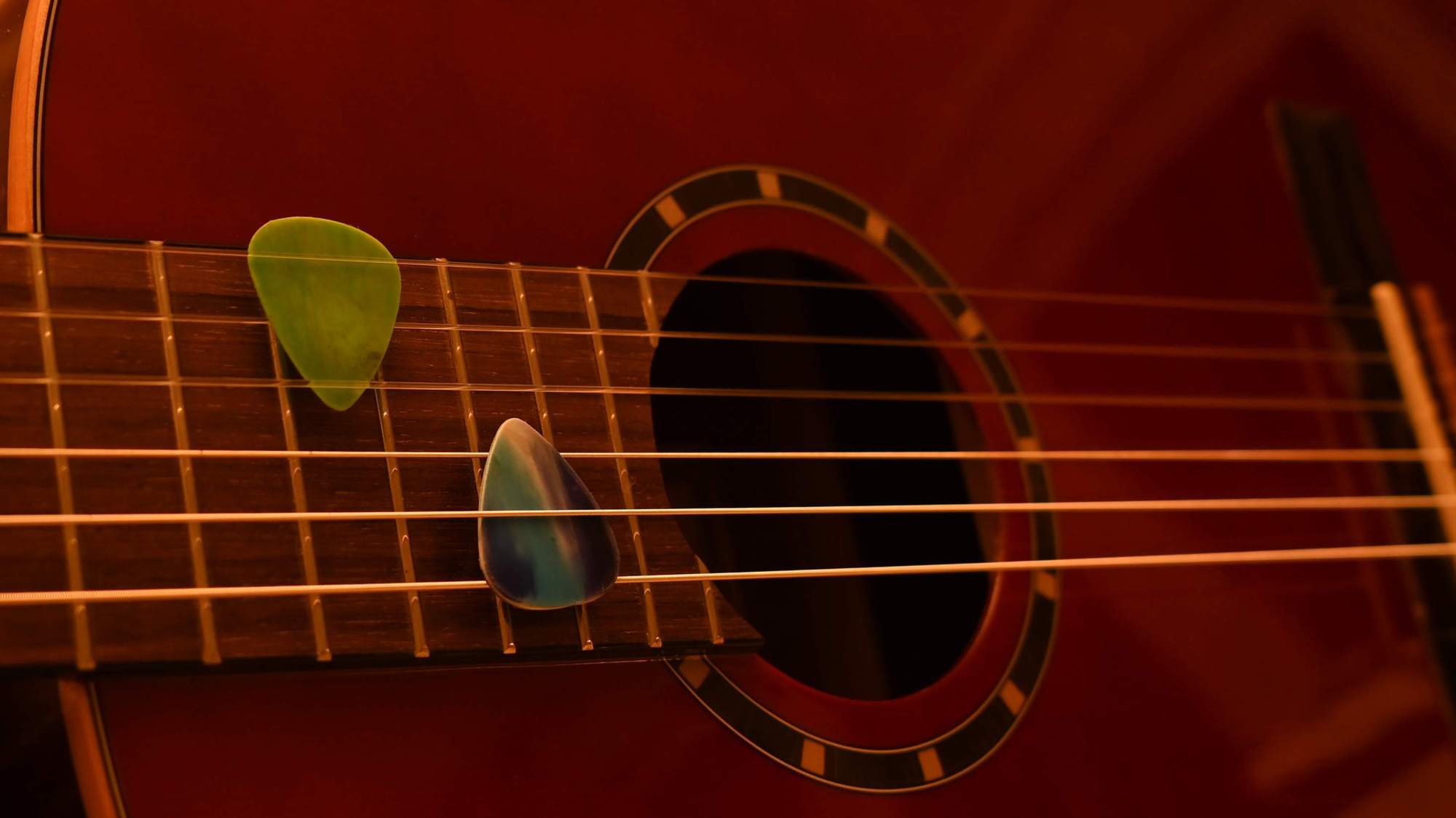 Zwei Trash Picks aus Plastikmüll zwischen den Saiten einer Gitarre.